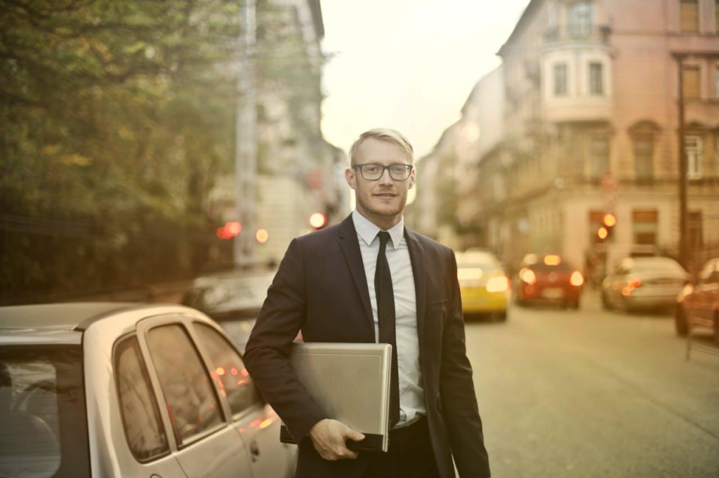 Photo d'un homme qui porte une costume et la un Pc portable à la main